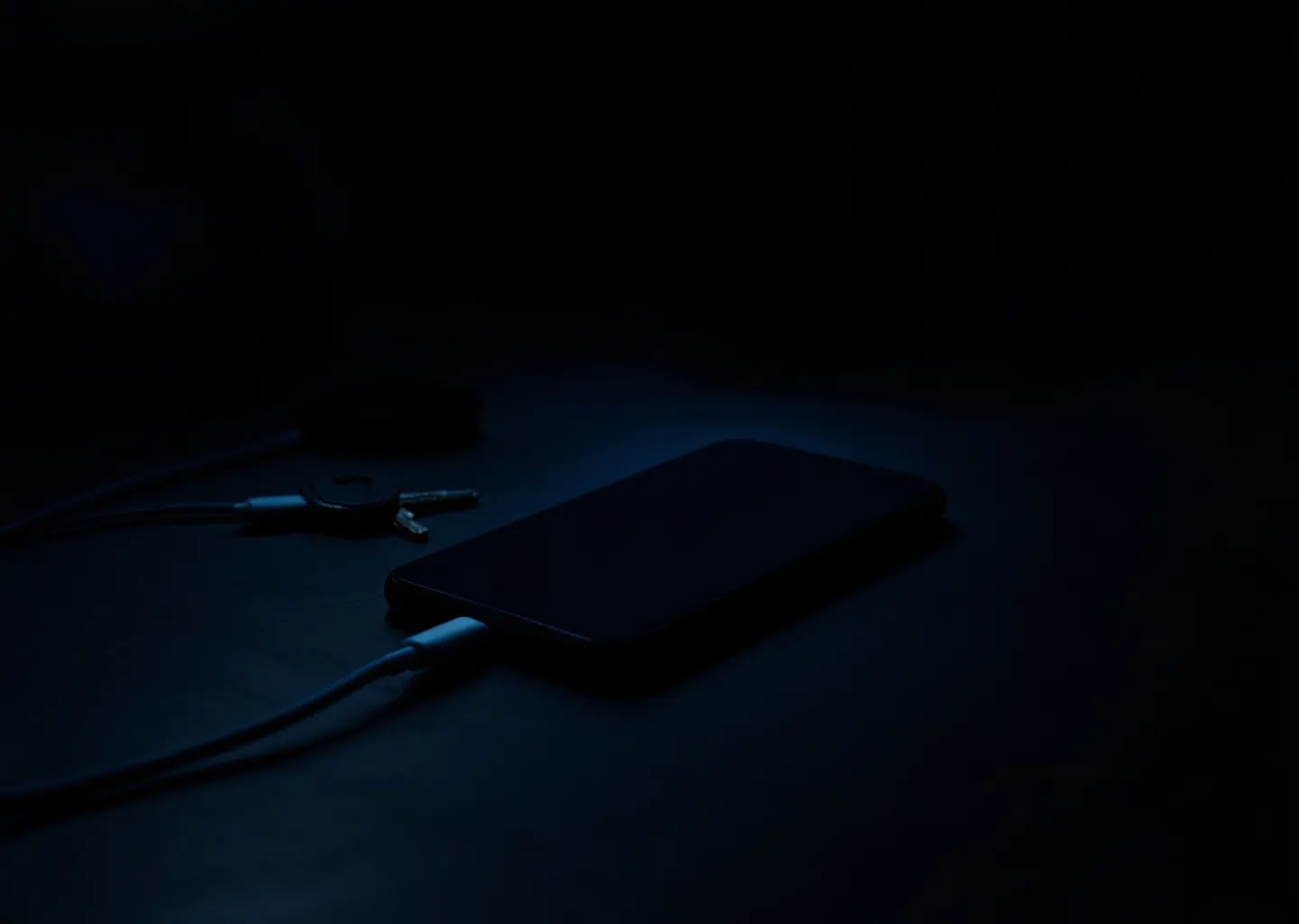 Smartphone posé sur une table dans une pièce sombre, écran faiblement allumé