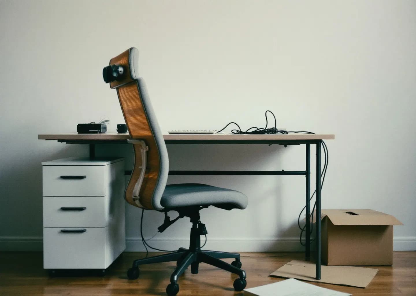 Bureau vidé après un départ : plan de travail nu, câble débranché et carton posé au sol