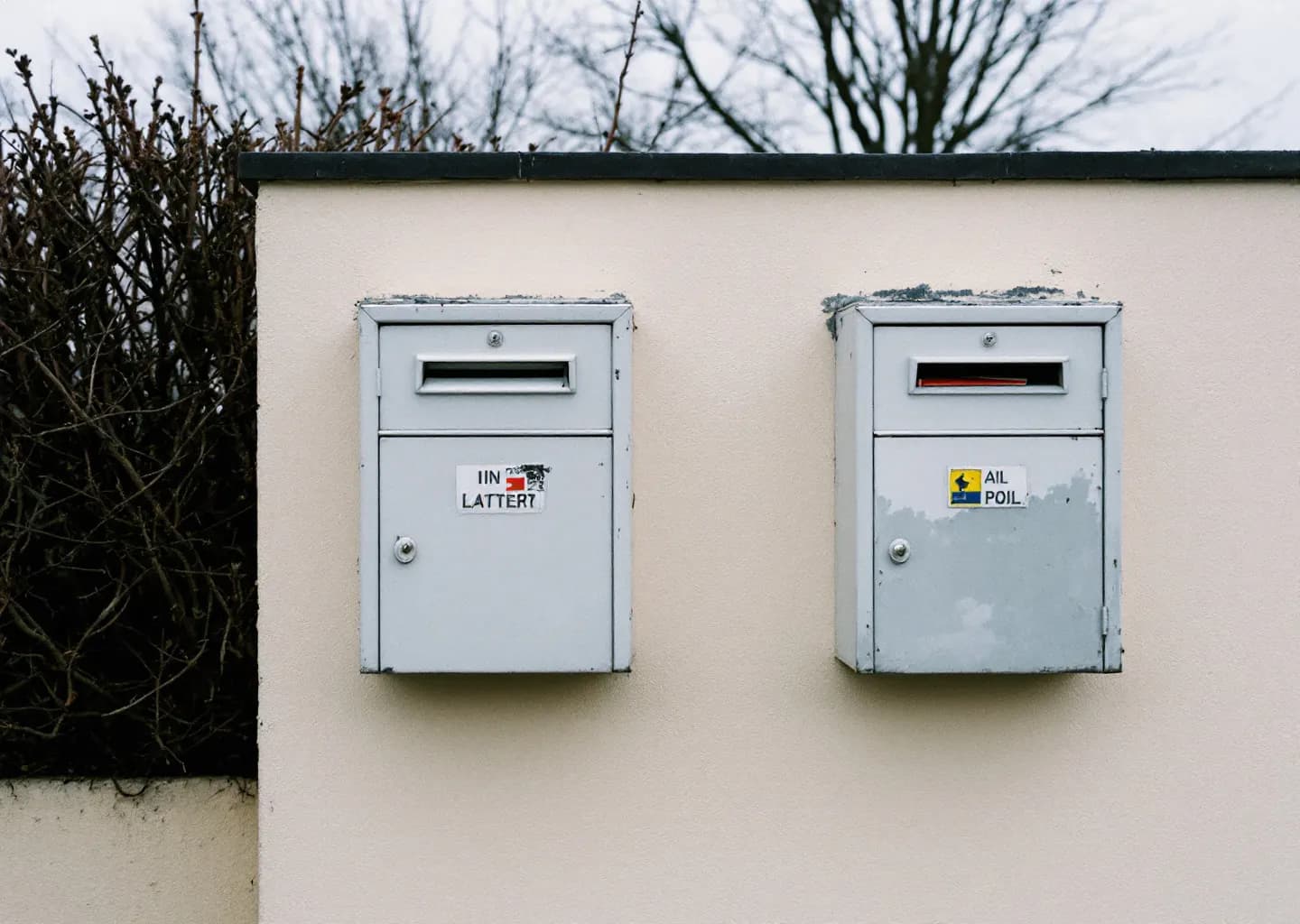 Deux boîtes aux lettres côte à côte sur un mur résidentiel, l'une entrouverte