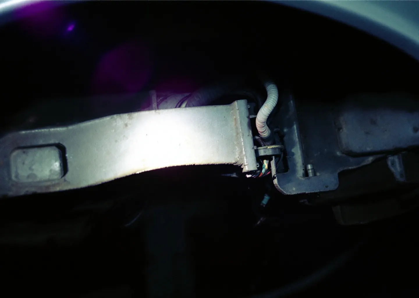 Passage de roue d'un véhicule photographié de près dans un garage, faisceau de lampe éclairant le renfoncement